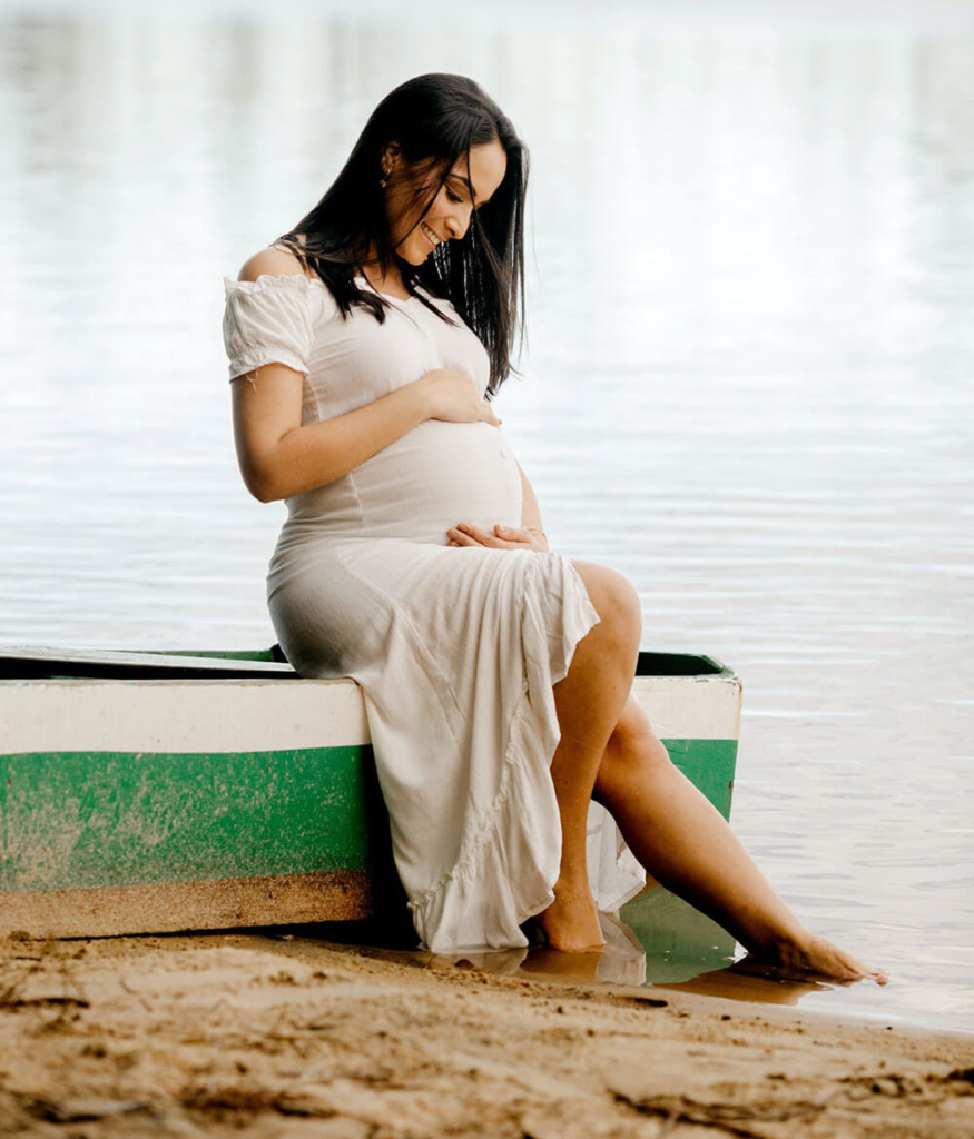 Zwangere vrouw zit bij het water | Wanneer geboortekaartjes versturen?